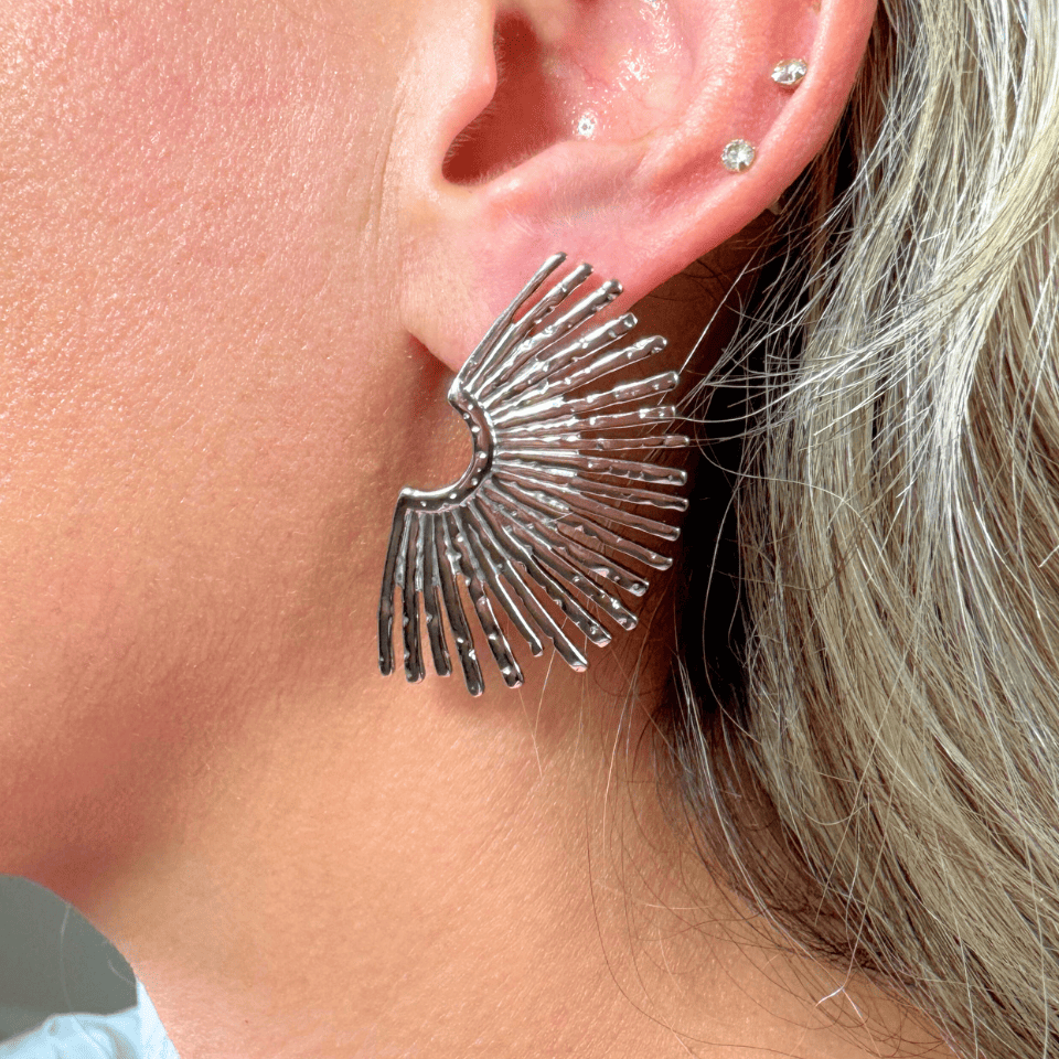 Close-up of a person wearing a silver fan-shaped earring.