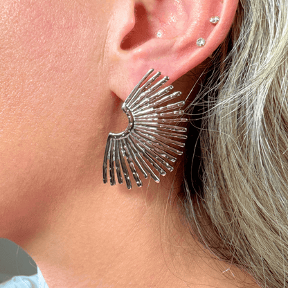Close-up of a person wearing a silver fan-shaped earring.