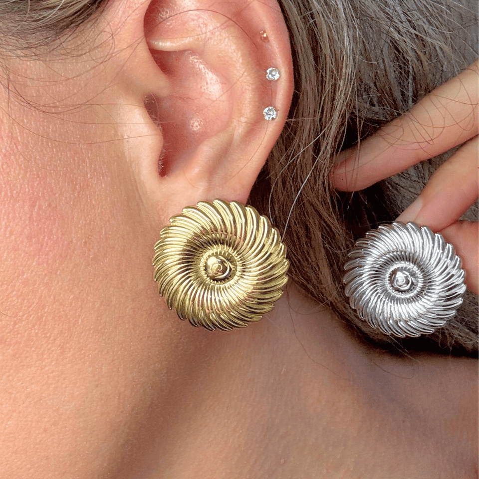 Close-up of a person wearing gold and silver spiral earrings.